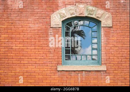 Grün bemalte Kunst und Kunsthandwerk Fensterrahmen in den frühen 1900er roten Backsteinmauer. Stockfoto