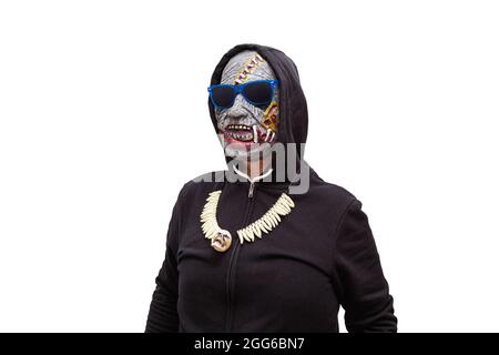 Ein Mann, der in einer Zombie-Maske verkleidet ist und ein schwarzes Kapuzen-Sweatshirt trägt, trägt eine Sonnenbrille mit blauen Rahmen. Stockfoto