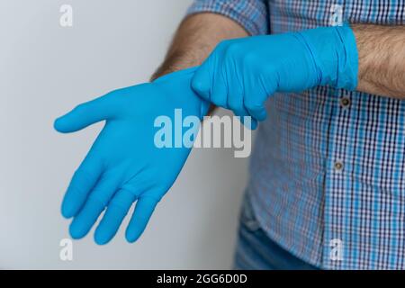 Hände eines Mannes mit blauen Schutzhandschuhen aus Gummi Stockfoto