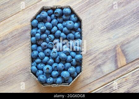 Frische reife Walderbeeren in Pappkarton vom Markt auf rustikalem Tisch. Flach liegend. Speicherplatz kopieren Stockfoto