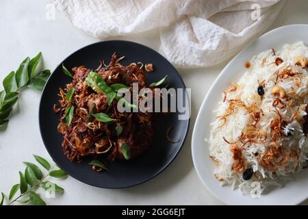 Würziger Hähnchenbraten im Kerala-Stil, serviert mit Ghee-Reis aus Basmati-Reis, garniert mit gebratenen Zwiebeln und Cashews. Eine beliebte Kombination aus Speisen Stockfoto