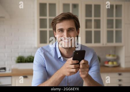 Porträt eines lächelnden jungen Mannes, der das Smartphone in den Händen hält. Stockfoto