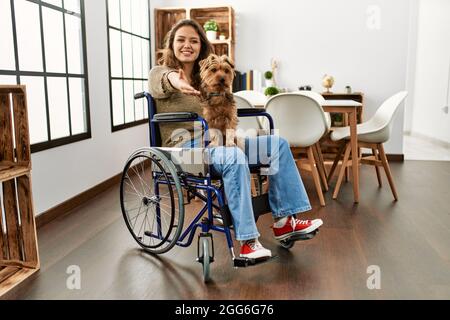 Junge hispanische Mädchen sitzt auf dem Rollstuhl zu Hause schlafen müde träumen und posieren mit den Händen zusammen, während lächelnd mit geschlossenen Augen. Stockfoto