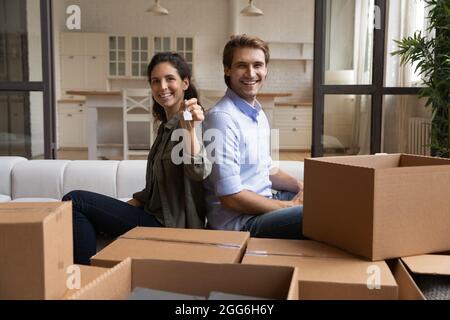 Glückliches junges Paar Hausbesitzer zeigt Schlüssel aus dem Haus. Stockfoto