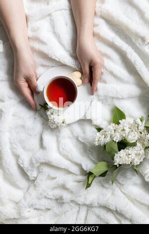 Jasminblüten Bouquet. Tasse Kaffee in einer weiblichen Hand. Draufsicht, minimales flaches Lay Stockfoto