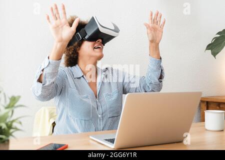 Ältere afrikanerin, die im Heimbüro ein VR-Virtual-Reality-Headset verwendet – Technologie-Geschäftstrend und Lifestyle-Konzept – Konzentration auf den Mund Stockfoto