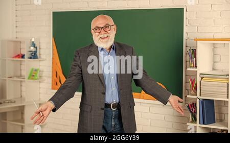 Liebende Mathematik. Werde gut in Mathematik. Stamm im Klassenzimmer. Senior Mann Lehrer verwenden Werkzeug an der Tafel. Bärtiger Tutor in Brille. Zurück zur Schule Stockfoto