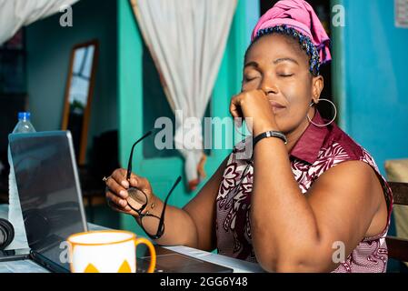 Reife Frau sitzt im Wohnzimmer mit Laptop denken. Stockfoto