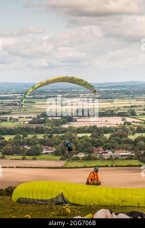 Firle, Lewes, East Sussex, Großbritannien. August 2021. Der morgendliche Nebel, der vom Norden her weht, bringt Gleitschirmflieger zu den herrlichen South Downs. Piloten starten über das Farmland des Anwesens Firle. Kredit: David Burr/Alamy Live Nachrichten Stockfoto