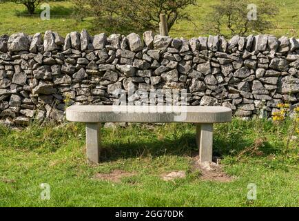 Gedenkbank aus massivem, fossilem, krinoidalem Marmor, zum Gedenken an David Wright, einen Pflanzenliebhaber in Deep Dale im Derbyshire Peak District, Großbritannien Stockfoto