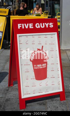 Schild mit Milchshake vor einem Burger-Restaurant mit fünf Männern in Liverpool Stockfoto