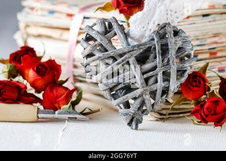 Weidenherz, Stift, rote getrocknete Rosen und Stapel von Liebesbriefen. Retro-Stil Stockfoto