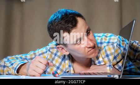 Junger Mann klopft an Laptop und wird wütend Stockfoto