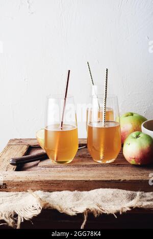 Bio-Apfelwein in Gläsern mit Stroh auf einem Holztisch. Stockfoto