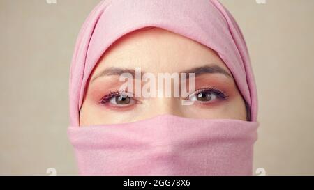 Muslimische Frau in einem rosa Kopftuch, das das Gesicht vollständig bedeckt Stockfoto