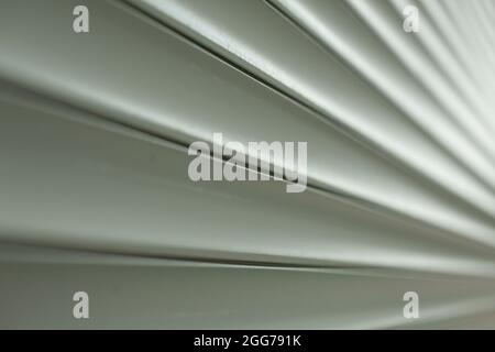 Jalousien-Struktur auf der Straße. Kunststoffoberfläche für die Fenster. Gerippte lange Lamellen. Grauer Hintergrund aus industriellem Material. Stockfoto