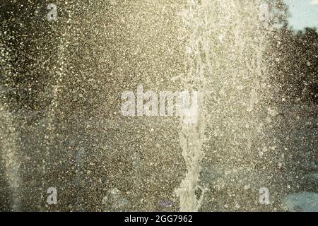 Wasserspritzer in die Luft. Ein Fantanstrahl auf dem Hintergrund des Himmels. Kleine Tropfen fliegen zu den Seiten. Stockfoto