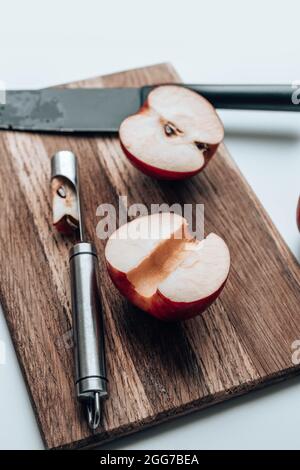 Frisch geerntete Äpfel auf Holzbrett mit einem Messer auf dem Küchentisch. Stockfoto