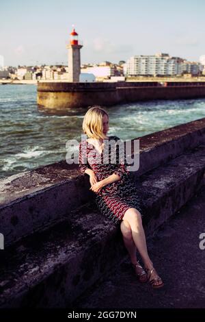 Eine Frau, die in der Nähe des Leuchtturms Farolim de Felgueiras in Porto, Portugal, sitzt. Stockfoto