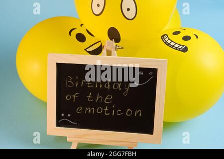 Gelbe Emoji-Ballons und ein Brett mit der Aufschrift Ereignisse auf blauem Hintergrund. Stockfoto