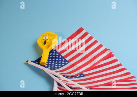 Gelbe Emoji-Ballons mit amerikanischen Flaggen auf blauem Hintergrund. Stockfoto