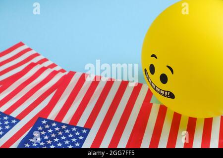 Gelbe Emoji-Ballons mit amerikanischen Flaggen auf blauem Hintergrund. Stockfoto