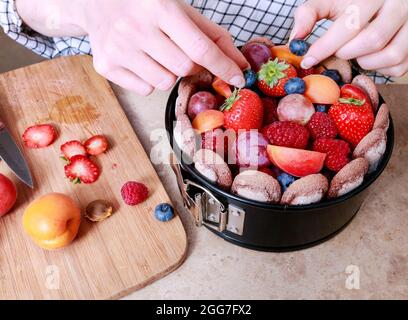 Frau bereitet französischen charlotte Kuchen mit Sommerfrüchten in der heimischen Küche. Party-Dessert Stockfoto