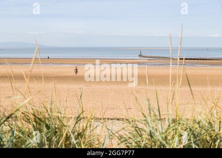 Drei der hundert Iron Men, die Antony Gormleys weiteren Platz am Crosby-Strand bilden, die im August 2021 über dem Marram-Gras gesehen wurden. Stockfoto