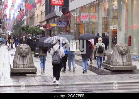 Stockholm, Schweden - 16. August 2021: Menschen in der Fußgängerzone Drottninggatan im Stadtzentrum mit Regenschirmen bei Regen. Stockfoto