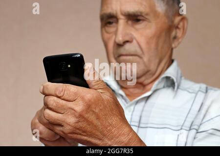 Älterer Mann, der Mobiltelefon benutzt und auf dem Smartphone-Bildschirm sieht. Konzept der Online-Kommunikation im Ruhestand, sms, Nachrichten lesen Stockfoto