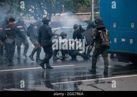 Bangkok, Thailand. August 2021. Die Bereitschaftspolizisten versuchen während der Demonstration einem Kollegen zu helfen. Tausende von regierungsfeindlichen Demonstranten fuhren ihre Fahrzeuge und blasse Hörner in einem „Car Mob“-Konvoi, in dem sie den Rücktritt von Prayut Chan-O-Cha, dem Premierminister Thailands, wegen des Scheiterns der Regierung bei der Bewältigung der COVID-19-Krise forderten. An einem Abend an der Kreuzung von DIN Daeng versammelten sich Hunderte regierungsfeindlicher Demonstranten von „Car Mob“ an der Kreuzung von DIN Daeng und kollidierten mit den Polizisten. (Foto von Peerapon Boonyakiat/SOPA Image/Sipa USA) Quelle: SIPA USA/Alamy Live News Stockfoto