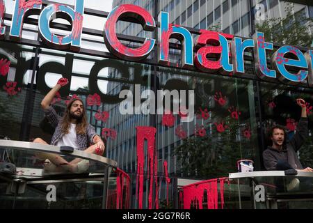 London, Großbritannien. August 2021. Umweltaktivisten von Extinction Rebellion erheben geballte Fäuste, nachdem sie während eines Blutgeldes-Marsches durch die City of London blutrote Farbe über die Fassade der Standard Chartered Bank verteilt haben. Extinction Rebellion beabsichtigte, die 23 Mrd. £hervorzuheben, die Standard Chartered seit dem Pariser Abkommen in fossile Brennstoffe investiert hat, während er die britische Regierung aufforderte, alle Investitionen in fossile Brennstoffe mit sofortiger Wirkung einzustellen. Kredit: Mark Kerrison/Alamy Live Nachrichten Stockfoto