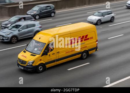 DHL Transporter fährt mit Autos auf der M25. Gelb Stockfoto