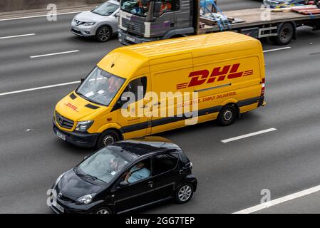 DHL-Transporter fährt auf der M25 mit Autos und einem LKW mit Geschwindigkeit Stockfoto