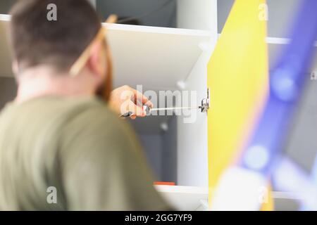Man dreht sich mit einem Schraubendreher in den Schrank Stockfoto