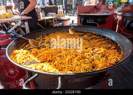 Ein Street-Food-Stand in Windsor, Großbritannien, der Paella verkauft, die in großen Pfannen über Gasbrennern gekocht wird. Stockfoto