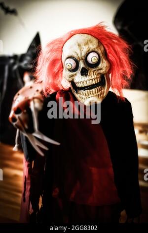 Boy verkleidet für eine halloween-Party mit einer schwarzen Tunika und einer schrecklichen Skelett-Maske mit googly blutunterlaufenen Augen und roten Haaren, selektiver Fokus, verti Stockfoto