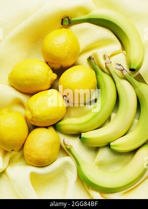 Blick von oben auf Bananen und Zitronen auf gelbem Tuch Stockfoto