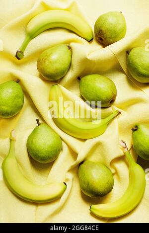 Ansicht von Bananen und Birnen auf gelbem Tischtuch Stockfoto