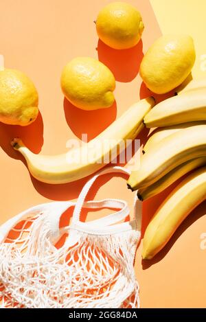 Ansicht von oben auf Bananen, Zitronen und Netzbeutel Stockfoto