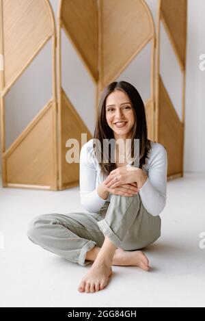 Studioaufnahme einer jungen Frau, die auf dem Boden sitzt Stockfoto