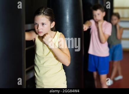 Jungen und Mädchen jabbing Boxsäcke im Fitnessstudio Stockfoto