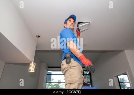 HLK-Techniker, der an einer Deckenventilanlage arbeitet Stockfoto