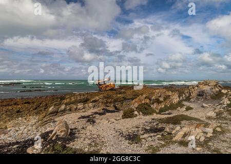 Zerklüftete Felsküste mit verrosteten Schiffswracks von Meisho Maru No.38 am Cape Agulhas in Südafrika, dem südlichsten Punkt des afrikanischen Kontinents. Stockfoto