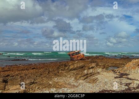 Zerklüftete Felsküste mit verrosteten Schiffswracks von Meisho Maru No.38 am Cape Agulhas in Südafrika, dem südlichsten Punkt des afrikanischen Kontinents. Stockfoto