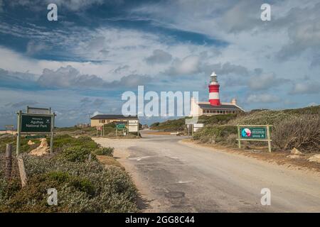 Eine Zufahrtsstraße zum Cape Agulhas National Park mit Cape Agulhas Lighthouse im Hintergrund, dem südlichsten Punkt des afrikanischen Kontinents. Stockfoto