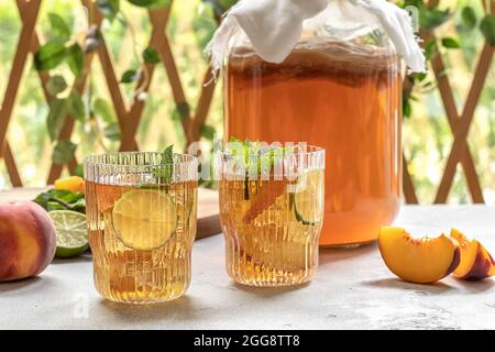 Hausgemachte Gärung. Kombucha-Tee leicht alkoholisches, leicht brausendes Getränk mit Pfirsich und Limette. Stockfoto