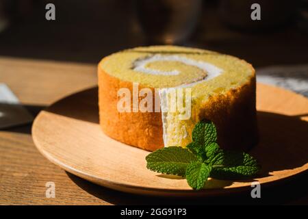 Swiss Roll ist eine Art Kuchen, der mit Schlagsahne, Marmelade oder Eisgetränk und 1 Tasse Milchtee gerollt wird Stockfoto