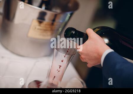 Der Kellner gießt erlesenen Rotwein in die Dekanter auf dem Tisch im Restaurant. Stockfoto