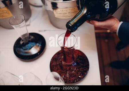 Der Kellner gießt erlesenen Rotwein in die Dekanter auf dem Tisch im Restaurant. Stockfoto